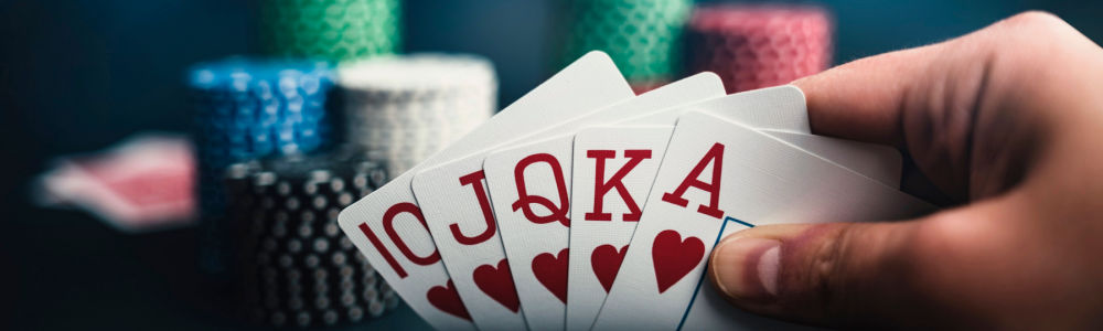 a hand showing us a royal flush poker hand with chips on the table in the background