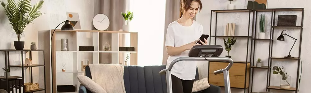 woman on her mobile while on a treadmill