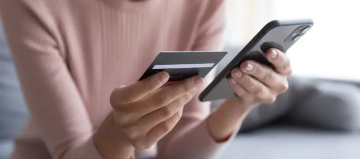 woman holding her phone and credit card making an online payment