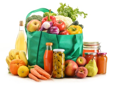 shopping bag full of groceries with more groceries on the table around the bag